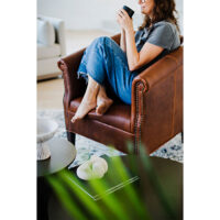 a detail shot of a custom lounge chair and a woman drinking coffee