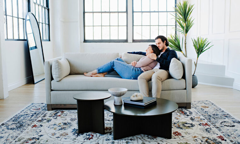 couple snuggling on a custom sofa with exposed wood base