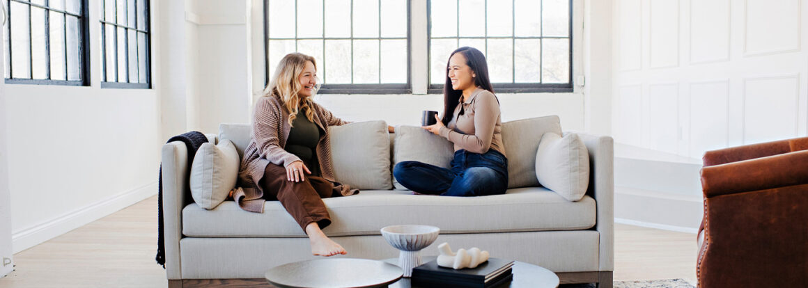 women having conversation on a modern white couch with wood base