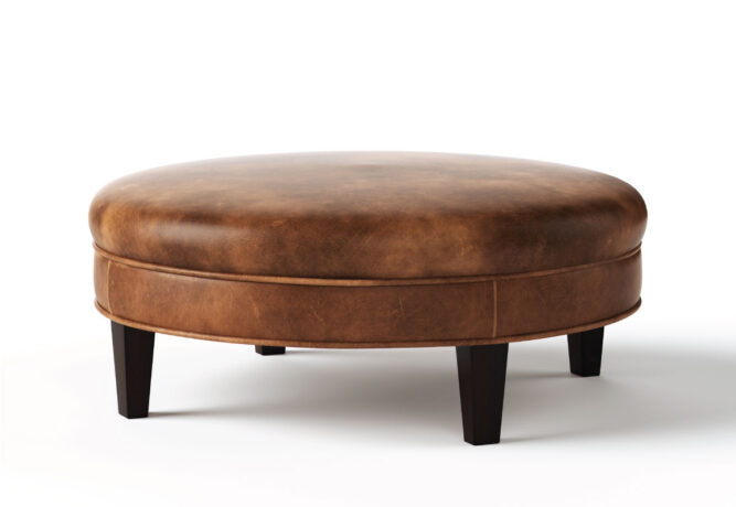 Round Carlisle ottoman from Vogel by Chervin in brown leather and espresso legs with a flat top