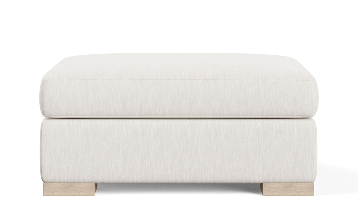 Front shot of the oversized, plush Broadway ottoman from Vogel by Chervin in a white fabric with light wood legs