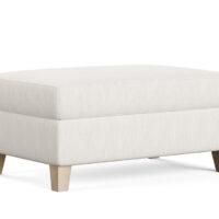 a transitional ottoman in a white fabric with oak legs